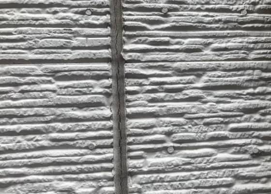 外壁のサイディングボードのクローズアップ写真。横方向に凹凸のある模様と接合部分が見える。