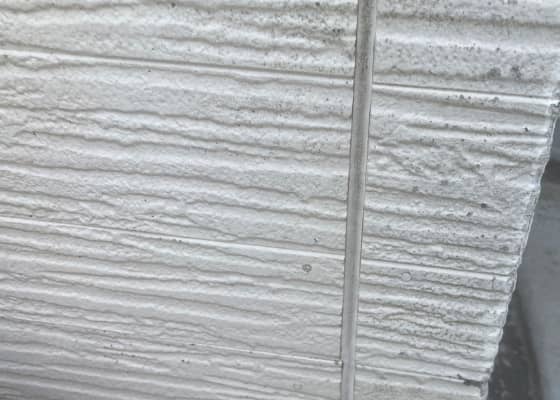 外壁の角部分。凹凸のある白いサイディングボードが使われており、接合部が中央にある。