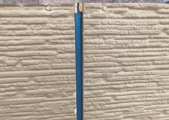 建物の外壁に青いテープが貼られている部分。横線模様のサイディングと目地が確認できる