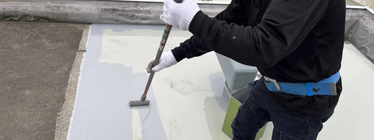 防水作業の詳細、ローラーを使用して表面に防水材を均一に広げている作業員