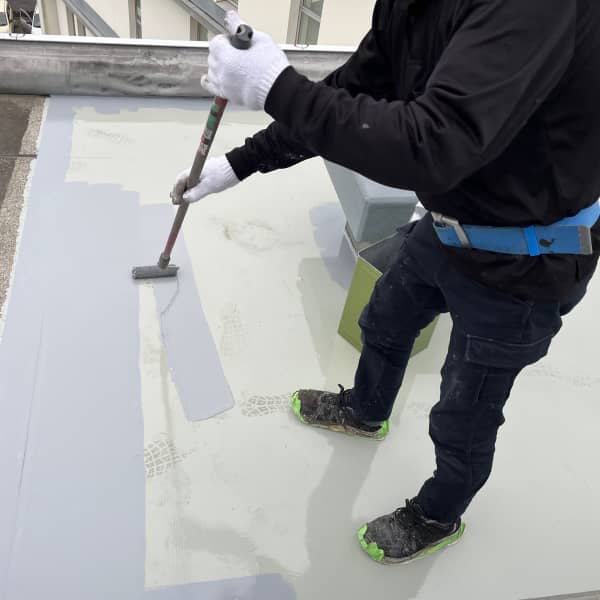 塗料ローラーでコンクリートの表面に塗装を施す建設工事中の風景